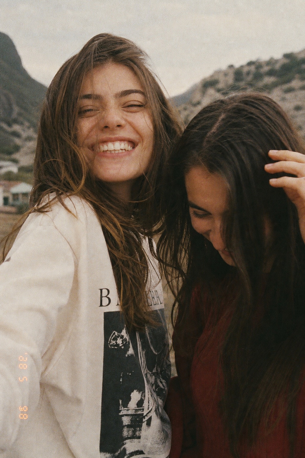 Two friends laughing close to the camera on a windy day, date stamp in the corner