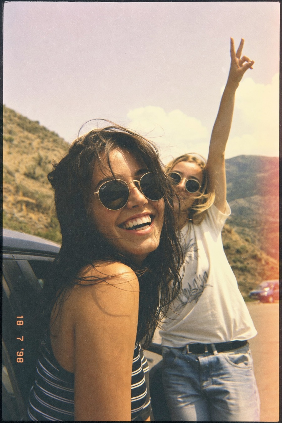Two friends laughing in a candid photograph with the hard flash of a disposable camera